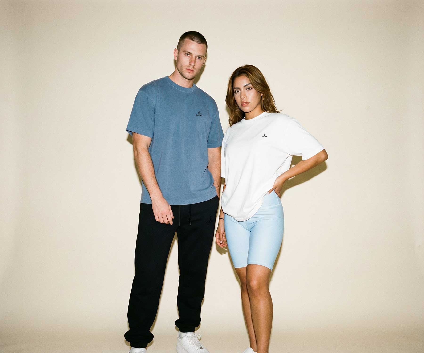 Two people wearing matching outfits against a plain background