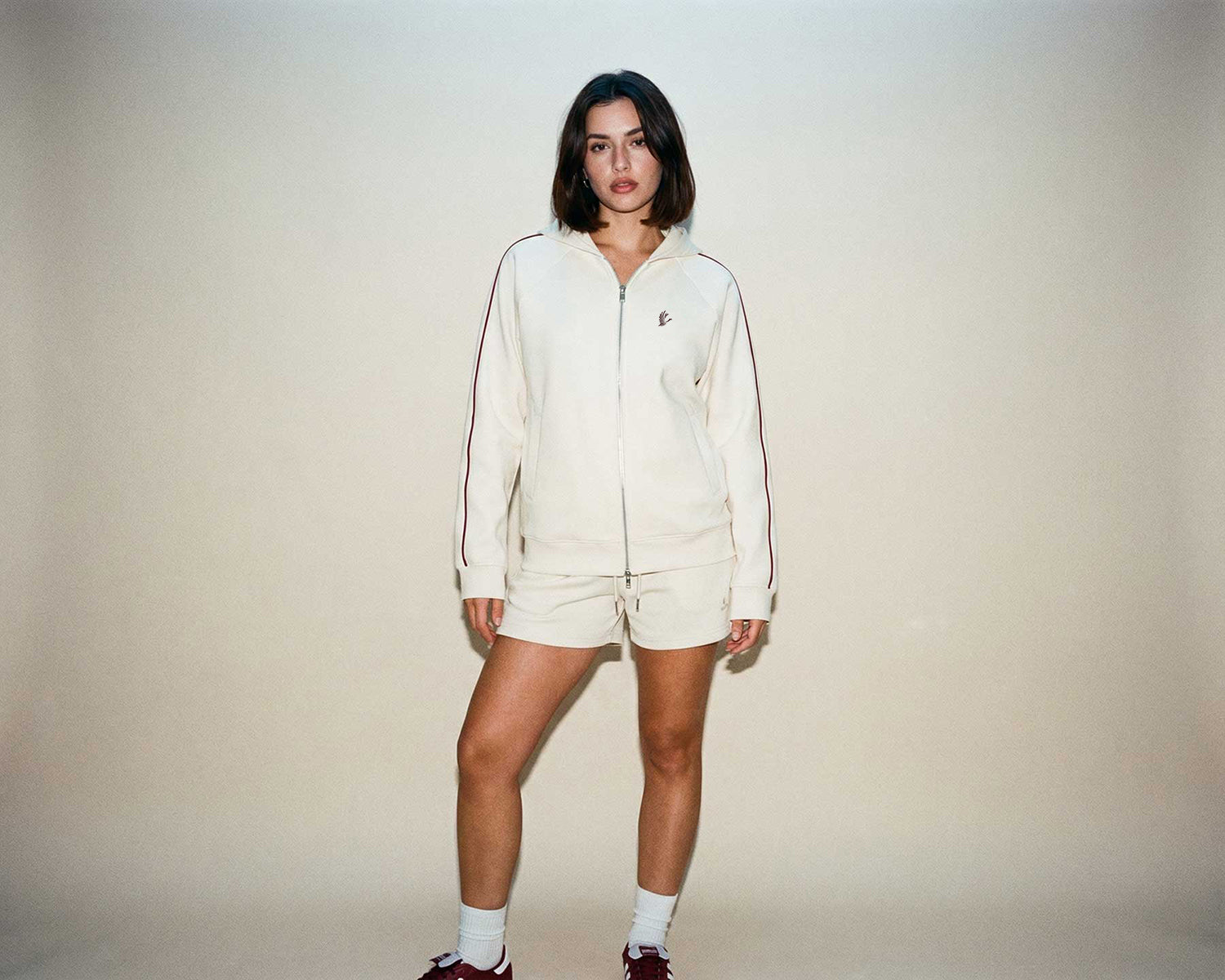 Person wearing a cream-colored tracksuit against a plain background